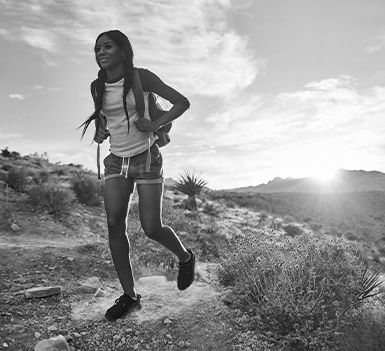 a black and white photo of a girl hiking during the day