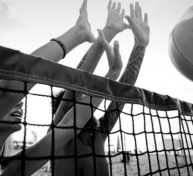 a black and white image of people playing volleyball on the beach